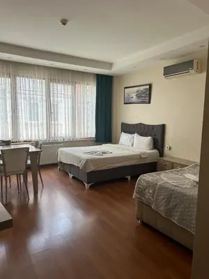 a hotel room with two beds and a table and chairs at Birinci Apart Hotel in Istanbul