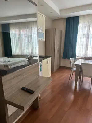 a living room with a table and a bedroom at Birinci Apart Hotel in Istanbul