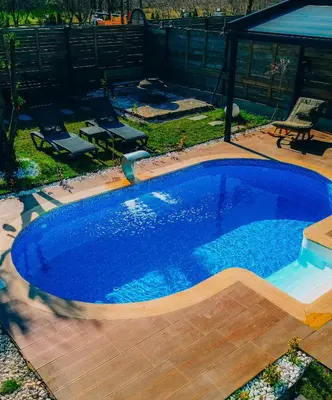 a large blue pool with a wooden deck and a patio at 7Sense Nature Resort in Sapanca