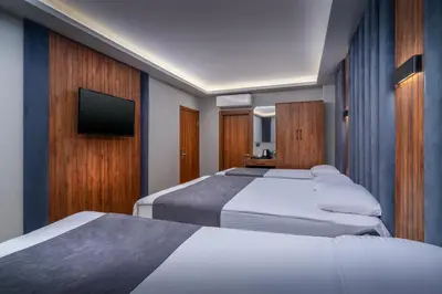 a hotel room with three beds and a flat screen tv at Elite Port Hotel Istanbul Airport in Arnavutköy