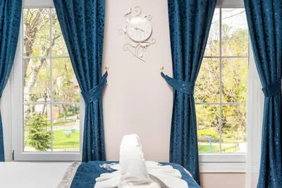 a bedroom with blue curtains and a clock on the wall at Begonville Corner in Istanbul