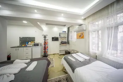 two beds in a room with a kitchen and two windows at Amida Family apart in Istanbul