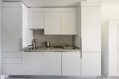 a white kitchen with white cabinets and a sink at Cozy Bright Studio w Parking, PoolViews! #237 in Istanbul