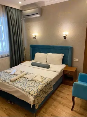 a bedroom with a bed with a blue headboard and a blue chair at Riverland Suites Apart Hotel in Istanbul