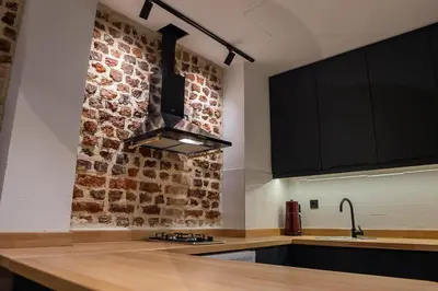 a kitchen with black cabinets and a brick wall at Alness Residence in Istanbul