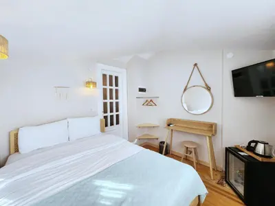 a white bedroom with a bed and a television at Aya Butik Otel in Buyukada