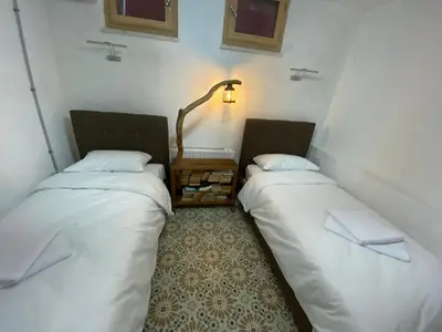 two beds in a room with a lamp on the wall at Balat Historical House in Istanbul