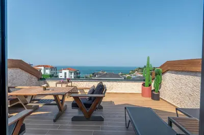 a patio with a table and chairs and the ocean at La Miel Şile in Sile
