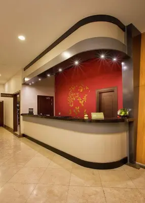 a lobby with a counter with a red wall at Hilton Garden Inn Kocaeli Sekerpinar in Şekerpınarı