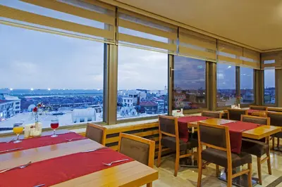 a restaurant with tables and chairs and large windows at Delta Hotel Istanbul & Old City in Istanbul