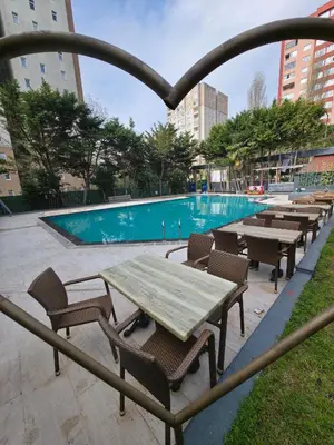 a wooden table and chairs next to a swimming pool at Gardan Hotel in Beylikduzu