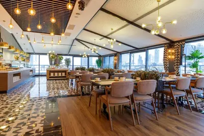 a restaurant with tables and chairs and large windows at Ramada Encore by Wyndham Istanbul Sisli in Istanbul