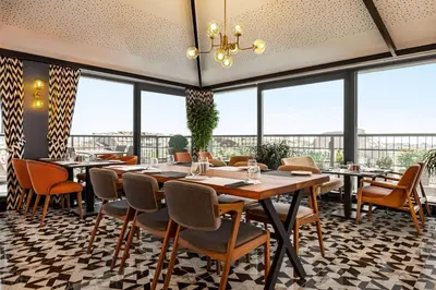 a restaurant with tables and chairs and large windows at Ramada Encore by Wyndham Istanbul Sisli in Istanbul