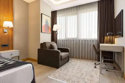 a hotel room with a bed and a chair and a desk at Ramada Encore by Wyndham Istanbul Sisli in Istanbul