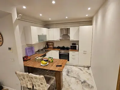a kitchen with white cabinets and a wooden counter top at PERFECT RESİDENCE TAKSİM, 2 BEDROOM, POOL, Gym, Sauna in Istanbul
