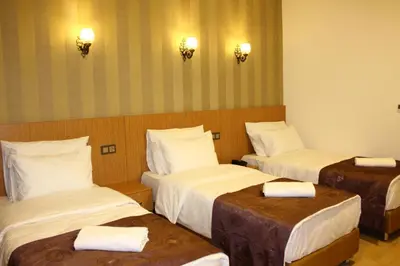 a hotel room with three beds with white sheets at Melidium Hotel in Beylikduzu