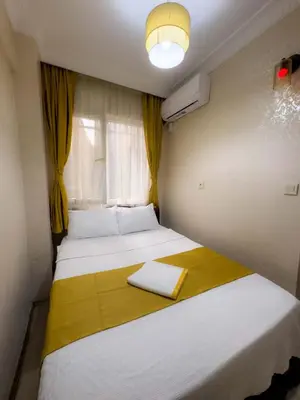 a small bedroom with two beds and a window at Öz Dünya Suites Apartment in Istanbul