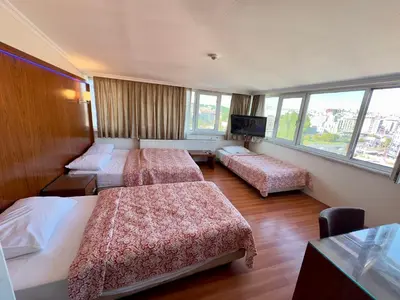 a hotel room with three beds and a flat screen tv at Hotel Nayla in Istanbul