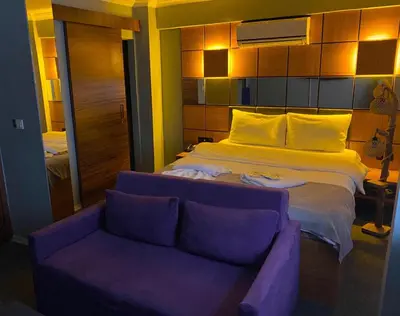 a bedroom with a large bed and a purple couch at Kadıköy Linda Hotel in Istanbul
