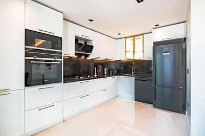 a kitchen with white cabinets and a black refrigerator at Homie Suites - Newly Built Seaside Apartments on Bakırköy Shore in Istanbul