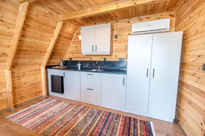 a kitchen with white cabinets and a rug in a log cabin at Aronia Bungalow in Elmalık