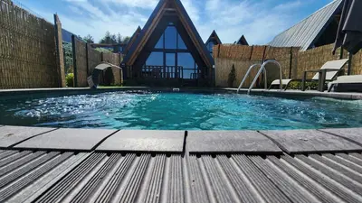 a large swimming pool with a church in the background at Aronia Bungalow in Elmalık