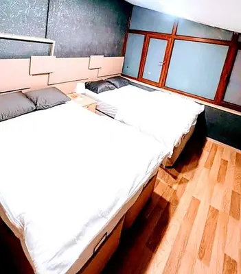 two beds in a room with wooden floors and windows at Family apartment in Istanbul