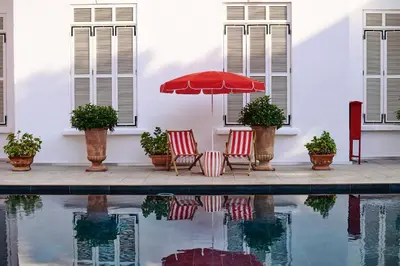 two chairs and an umbrella next to a swimming pool at Büyükada Splendid Palace Hotel in Buyukada