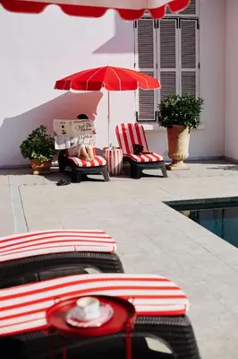 a pool with two chairs and a red umbrella at Büyükada Splendid Palace Hotel in Buyukada