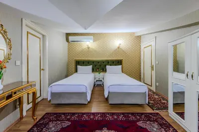 a hotel room with two beds and a mirror at Lemis Suite Istanbul in Istanbul