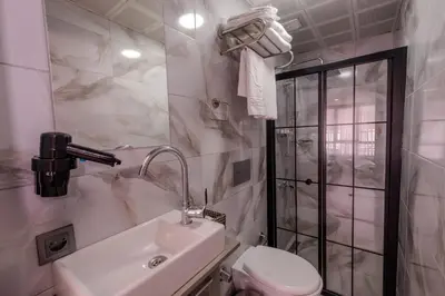 a white bathroom with a toilet and a sink at Rubby Kadıköy in Istanbul