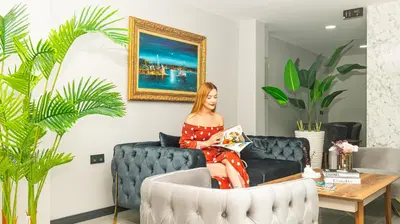 a woman sitting on a couch reading a magazine at Elite Marmara Bosphorus Çamlıca in Istanbul