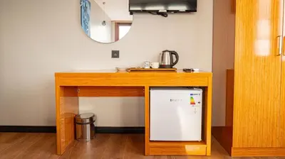 a small refrigerator under a wooden table with a mirror at Elite Marmara Bosphorus Çamlıca in Istanbul
