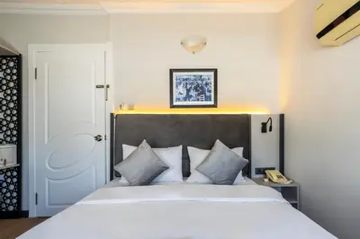 a bedroom with a white bed with a black headboard at Taksim Trust Hotel in Istanbul