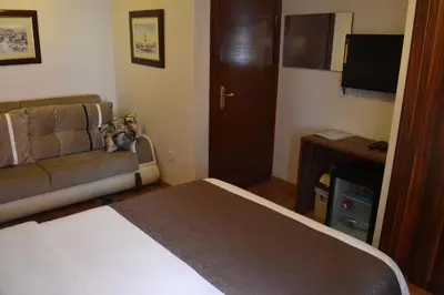 a bedroom with a bed and a couch and a television at New Fatih Hotel in Istanbul