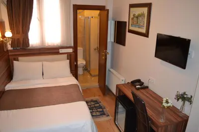 a room with two beds and a television and a bathroom at New Fatih Hotel in Istanbul