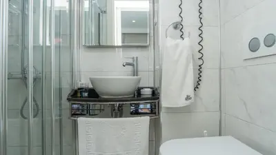 a white bathroom with a sink and a shower at Ten Rooms Istanbul Hotel in Istanbul
