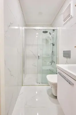 a white bathroom with a shower and a toilet at Charming Bagdat Avenue Hideaway, Near Marina in Istanbul
