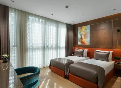 a bedroom with two beds and a chair at Nex Hotel & Spa Istanbul in Istanbul