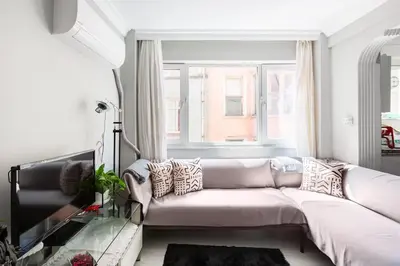 a living room with a white couch and a window at Practical and Cozy Flat Near Taksim İstikal in Istanbul