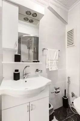 a white bathroom with a sink and a mirror at Practical and Cozy Flat Near Taksim İstikal in Istanbul
