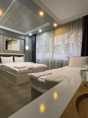 a bedroom with two beds and a table and windows at Ufuk Hotel in Istanbul