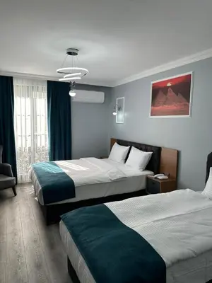 a hotel room with two beds and a chair at Asgard Hotel in Beylikduzu