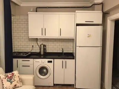 a kitchen with white cabinets and a washing machine at The rooms hotel in Kumbağ