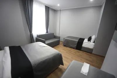 a hotel room with two beds and a chair at Yuvam Vari Hotel in Istanbul