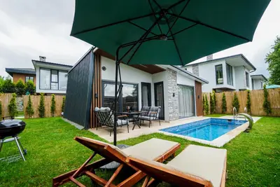 a backyard with a pool and an umbrella at Vital Home Sapanca Isıtmalı Havuzlu Villa&Bungalov in Sapanca