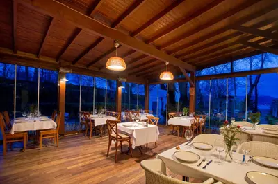 a restaurant with white tables and chairs and windows at Beta Home Sapanca in Sapanca