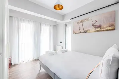 a white bedroom with a bed and a painting of a deer at Charming Bright New 2BD1Bath Home wparking!#339 in Istanbul