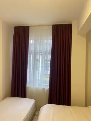 a bedroom with two beds and a window with red curtains at HOTEL yeniKAPI in Istanbul