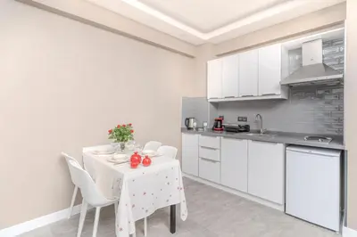 a white kitchen with a table and white cabinets at Olea Suites Otel in Gemlik